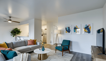 Everett apartment for rent - A living room with a grey sofa, a blue chair, a white coffee table, and a painting on the wall.