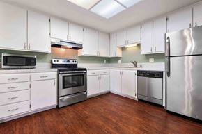 Fremont apartment for rent - 3-Bedroom Apartments in Fremont, CA - Logan Park - Kitchen with White Cabinets, Stainless Steel Appliances, Microwave, Dishwasher, and Wood-Style Flooring.