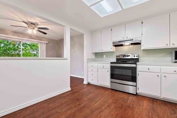 Fremont apartment for rent - a kitchen with white cabinets and a stove and a ceiling fan