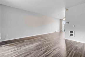 San Jose apartment for rent - Three-Bedroom Apartments in San Jose, CA - Los Gatos Creek - Empty Living Room with Wood-Style Flooring, Light Gray Walls, White Baseboards, Vent, Electrical Outlets, Light Fixture, and a Glass Door.