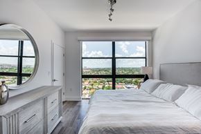 Miami apartment for rent - One-Bedroom Apartments in Miami, FL - MB Station - Bright Bedroom With Large Picture Window, Plush Bed, Modern Dresser And Mirror, And Sweeping City Views.