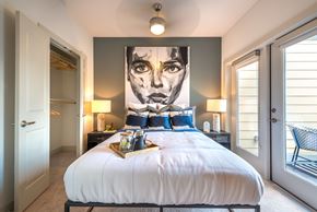 Dallas apartment for rent - A bedroom with a large bed and a painting on the wall.