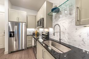 Dallas apartment for rent - A modern kitchen with a stainless steel refrigerator and a marble backsplash.
