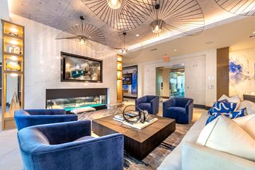 Dallas apartment for rent - A living room with a fireplace, blue chairs, and a painting on the wall.