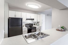 Coon Rapids apartment for rent - a kitchen with white cabinets and black appliances