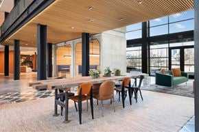 Houston apartment for rent - A modern dining area with a long table and chairs inside the Laura community lounge.