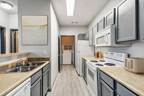 Nashville apartment for rent - Nashville, TN Apartments - Parc at Metro Center - long kitchen with white appliances and wooden floors and Grey Cabinets