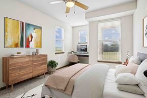 Bentonville apartment for rent - Pet-Friendly Rentals in Bentonville, AR – Parc at Bentonville – A bedroom with a bed, dresser, and a ceiling fan.