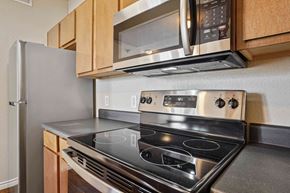 Maumelle apartment for rent - 1, 2 & 3-Bedroom Apartments for Rent in Maumelle, AR – Parc at Maumelle – A modern kitchen with a stainless steel stove and microwave above it.