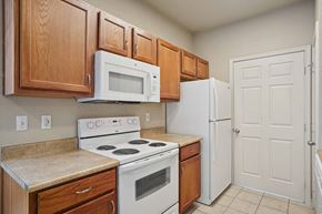 Rogers apartment for rent - Pet-Friendly Rentals in Rogers, AR – Parc at Rogers – A kitchen with a white stove and white refrigerator.