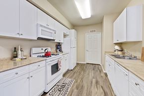 Upland apartment for rent - Two-Bedroom Apartments in Upland, CA - Park Central Apartments - Kitchen with Wood-Style Flooring, White Cabinetry, White Appliances, and Ceiling Light.