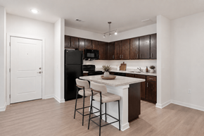 Clarkston apartment for rent - A kitchen with a black refrigerator and brown cabinets.