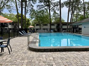 Gainesville apartment for rent - a resort style swimming pool with chairs and trees