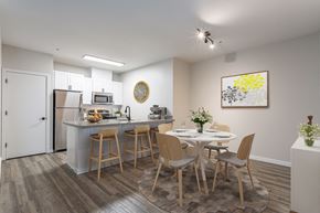 Sherwood apartment for rent - Pet Friendly Apartments in Sherwood OR - Cannery Row - Kitchen with Wood-Style Floor, Stainless Steel Appliances, White Cabinets, Granite-Style Countertops, Breakfast Bar with Stools, and 4-Seater Round Dining Set