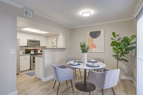 Moreno Valley apartment for rent - Two-Bedroom Apartments in Moreno Valley, CA - Ardella on Chagall - Dining Area with Hardwood-Style Flooring, Round Table and Four Chairs, Houseplant, and View of Kitchen.
