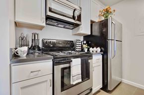 Daly City apartment for rent - One-Bedroom Apartments in Daly City, CA - Serra Commons - Kitchen with Stainless-Steel Appliances, White Cabinets, and Tiled Floor.