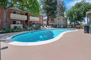 Milpitas apartment for rent - Milpitas, CA, Apartments - Spring Valley Apartments - Outdoor Swimming Pool With Curved Deck, Lounge Chairs, And Black Metal Fence.