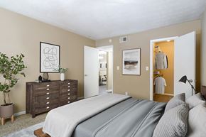 Marietta apartment for rent - A bedroom with a large bed and a dresser with a plant on top.