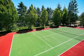 Bothell apartment for rent - A tennis court with red and green surface surrounded by trees.