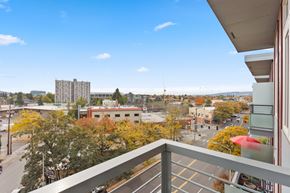 Portland apartment for rent - A balcony overlooks a city street with buildings and trees.