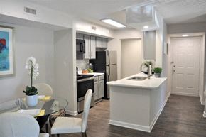 Greensboro apartment for rent - Modern apartment kitchen and dining area with gray cabinets, stainless steel appliances, and white countertops.