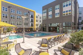 San Jose apartment for rent - A pool area with chairs and umbrellas in front of a building.