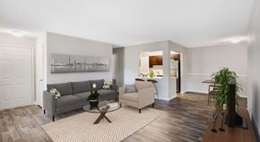 Peachtree City apartment for rent - A living room with a grey couch, a coffee table, and a potted plant.