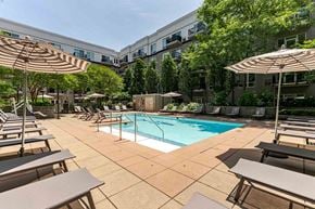 Stamford apartment for rent - A large outdoor pool area with sun loungers and umbrellas.