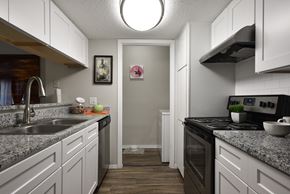 San Antonio apartment for rent - a kitchen with white cabinets and granite counter tops and a black stove