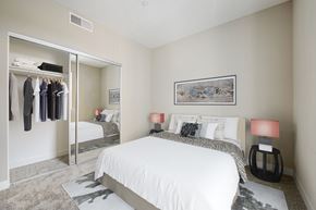 Long Beach apartment for rent - One Bedroom Modern Apartments in Long Beach CA - Urban Village - Carpeted Bedroom with a Large Bed, a Large Mirror-Door Closet, Black Nightstands, and Beige Walls
