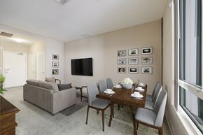 Long Beach apartment for rent - A living room with a grey couch, a wooden dining table and grey chairs.