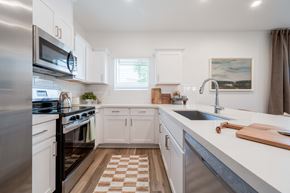 Tolleson apartment for rent - Tolleson, AZ, Townhomes Near Desert Sky Mall - Villas on Van Buren - Kitchen with Quartz Countertops and Modern Cabinetry, Tile Backsplash, Stainless Steel Appliances, and a Central Island.