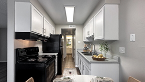 Denver apartment for rent - A kitchen with a black stove top oven and white cabinets.