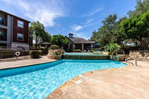 San Antonio apartment for rent - A swimming pool surrounded by a fence and trees.