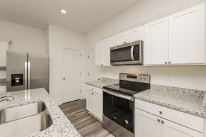 Zephyrhills apartment for rent - A kitchen with a stainless steel refrigerator, microwave, oven, and sink.