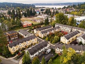 Kenmore apartment for rent - Apartments for Rent in Kenmore, WA - Northshore Townhomes - Aerial View of the Property Featuring Tan and Yellow Buildings with Grey Roofing, Surrounded by Lush Nature and Landscaping, with Nearby Lake in the Background.