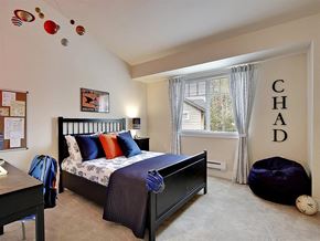 Kenmore apartment for rent - Three-Bedroom Apartments in Kenmore, WA - Northshore Townhomes - Bedroom with Carpeted Flooring, Bed, Nightstand with Lamp, Desk Chair, Bean Bag, Vaulted Ceiling, and Large Window.