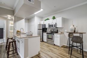 Rosenberg apartment for rent - a kitchen with white cabinets and stainless steel appliances and a bar with stools