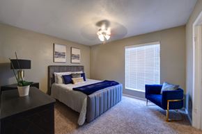 Houston apartment for rent - a bedroom with a bed and a chair and a window