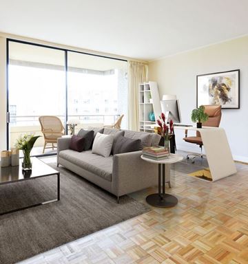 Washington apartment for rent - A living room with a grey couch, a coffee table, a chair, a potted plant, a bookshelf, and a painting on the wall.