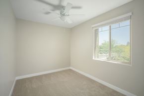 Surprise apartment for rent - A room with a ceiling fan and a window showing a view of trees.