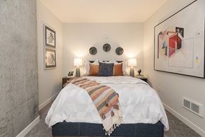Oakland apartment for rent - A bedroom with a bed covered in a white comforter and a striped blanket.