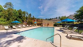 Augusta apartment for rent - Outdoor swimming pool at Broad on the Green in Augusta, Georgia with lounge seating and umbrellas surrounding the swimming pool.