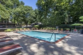Peachtree City apartment for rent - a resort style pool with chairs and trees