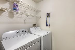 Peachtree City apartment for rent - two washers and a dryer in a laundry room with a shelf above them