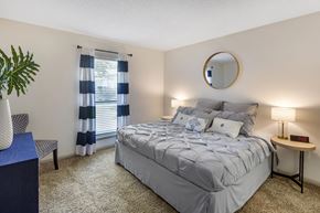 Peachtree City apartment for rent - a bedroom with a bed and a window with blue and white curtains