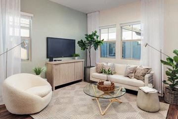 Apache Junction apartment for rent - A living room with a white couch, a white chair, a glass coffee table, and a television on a cabinet.