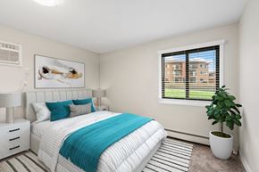 Eagan apartment for rent - A bedroom with a large bed and a potted plant.