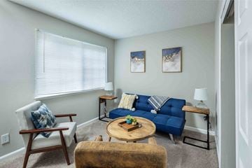 Raleigh apartment for rent - A living room with a blue couch and a wooden chair.