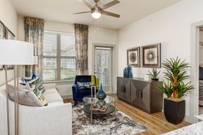 Saginaw apartment for rent - Luxury Apartments in Saginaw, TX with In-Unit Washer and Dryer - Grand at Saginaw - Living Room with a Ceiling Fan, Hardwood-Style Flooring, and an Oversized Window